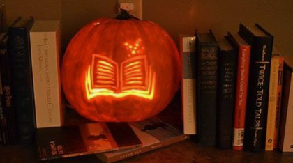 A book carved into a pumpkin on a bookshelf